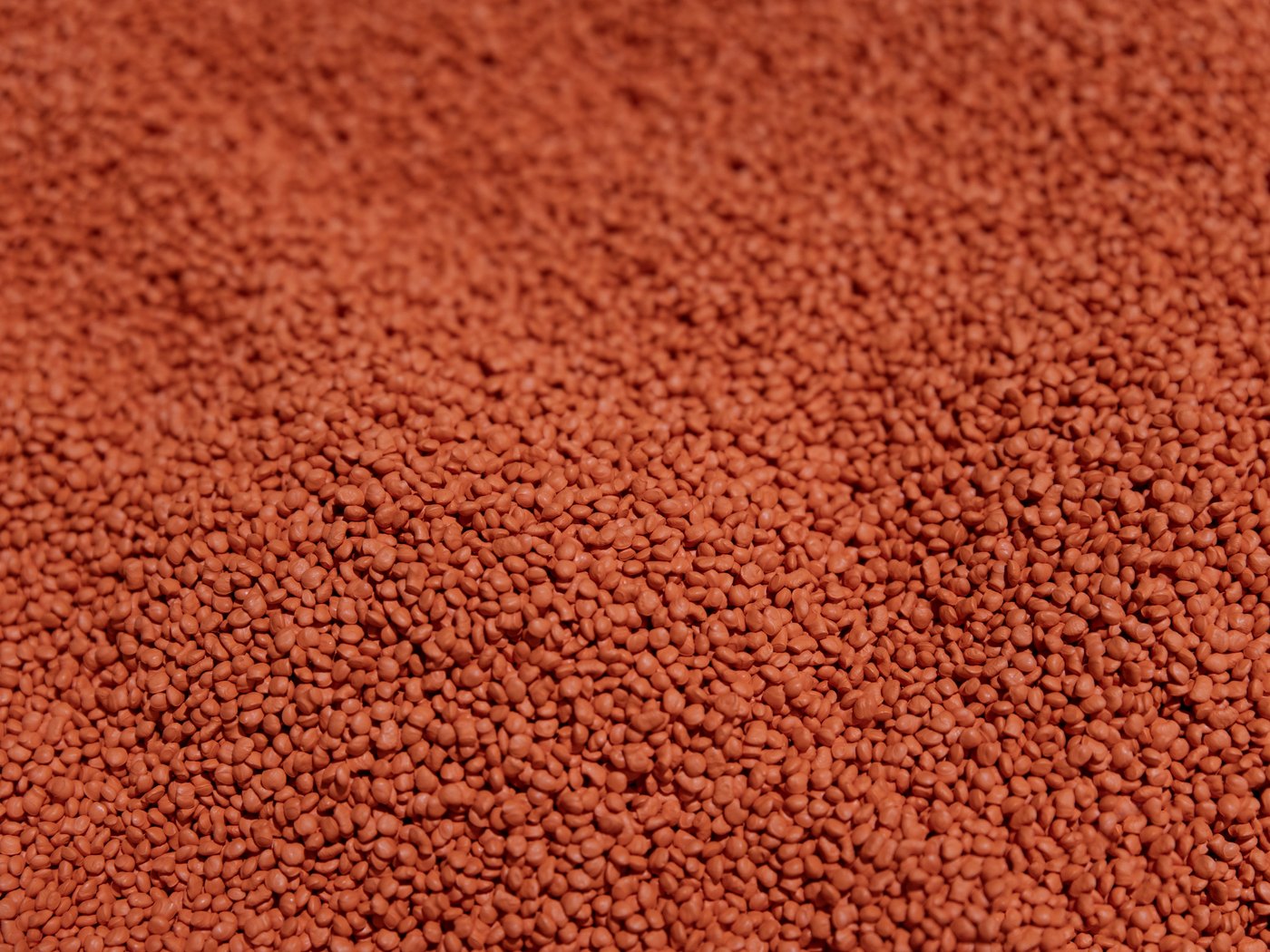 Close-up of orange HDPE resin pellets, the raw material used to manufacture our conduit